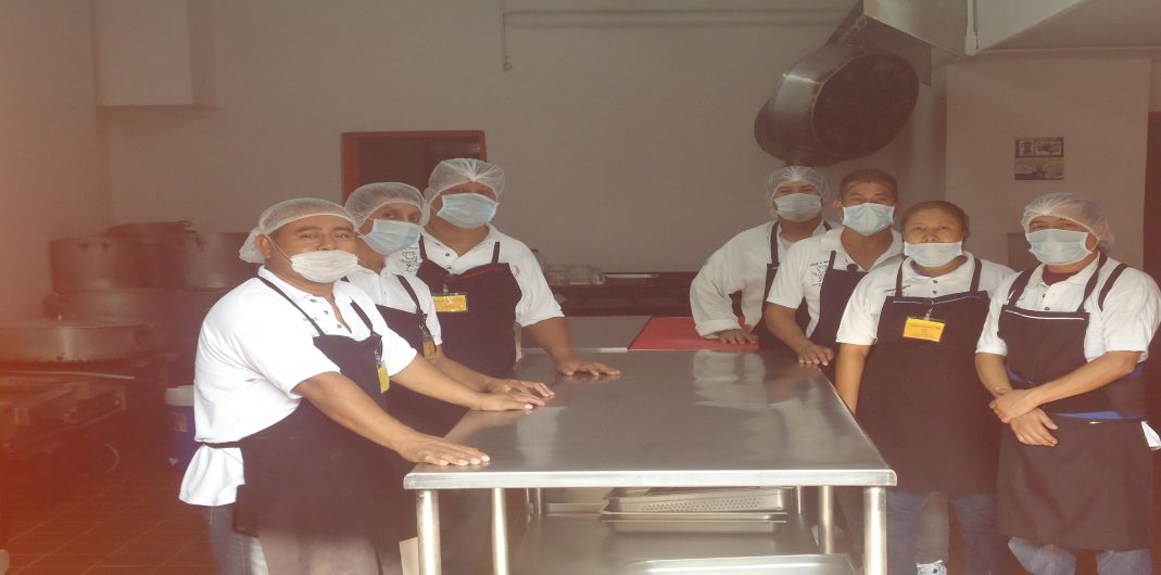 Personal de EGA México uniformado con cofia y cubrebocas en la mesa de trabajo